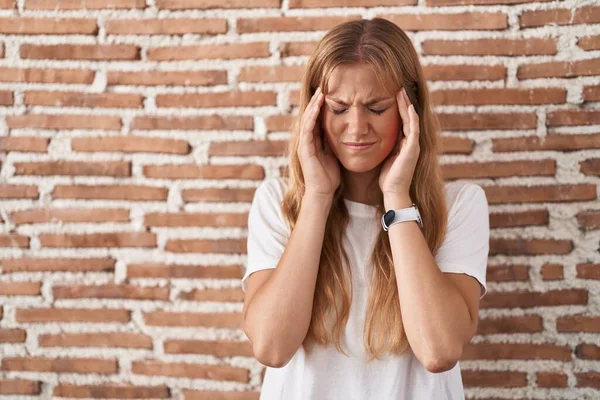 若い白人女性の頭の上に手でレンガの壁の上に立って 頭痛の種ので ストレス 片頭痛 — ストック写真