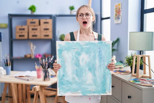 Young Caucasian Woman Holding Canvas Art Studio Angry Mad Screaming — Stock Photo, Image