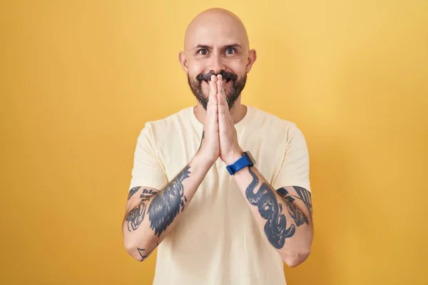 Sarı Arka Planda Dikilmiş Spanyol Dövmeli Bir Adam Elleriyle Dua — Stok fotoğraf