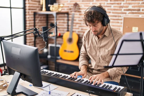 Young man musician playing piano keyboard at music studio