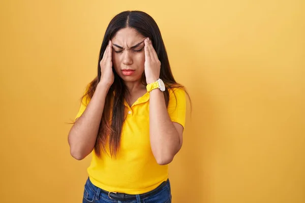 年轻的阿拉伯女人站在黄色的背景上 手扶着头 头疼是因为压力 偏头痛 — 图库照片