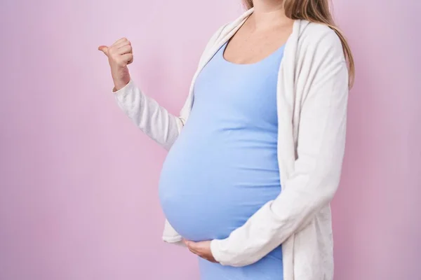 若いです妊娠中の女性を期待赤ちゃん 指を触れます妊娠中の腹を指します親指アップ側笑顔で幸せなオープン口 — ストック写真