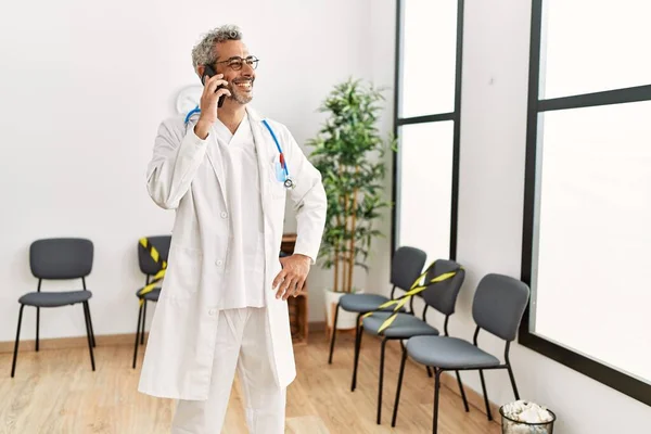 Medelålders Gråhårig Man Läkare Ler Säker Talar Smartphone Kliniken Väntrum — Stockfoto