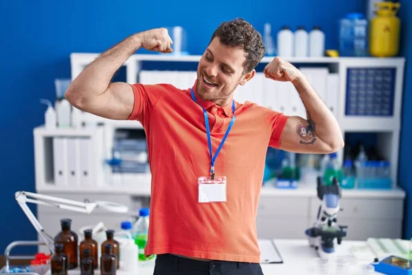 Young Hispanic Man Working Scientist Laboratory Showing Arms Muscles Smiling — Stock Photo, Image