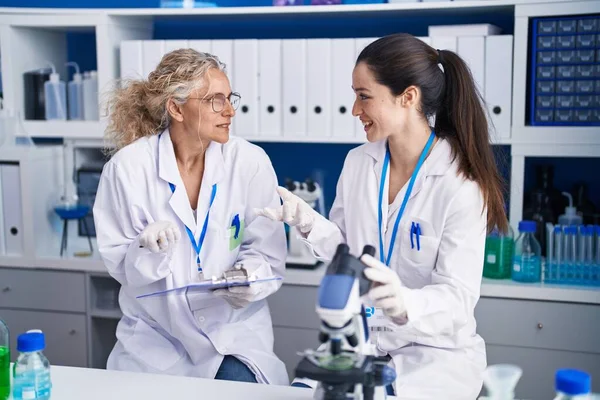 Duas Mulheres Cientistas Usando Microscópio Escrevem Documento Laboratório — Fotografia de Stock