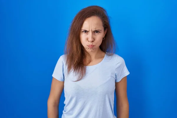 Brunette Vrouw Staat Blauwe Achtergrond Puffende Wangen Met Grappig Gezicht — Stockfoto
