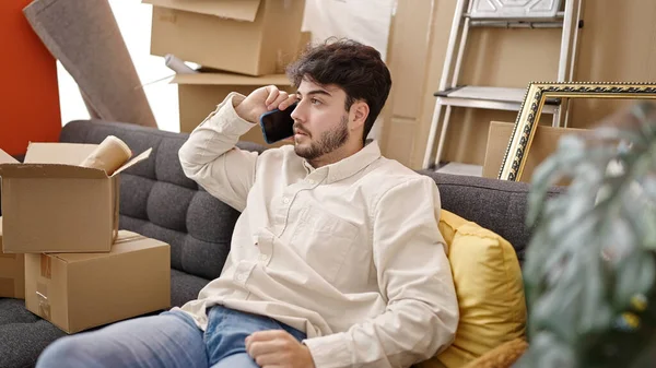 Ung Latinamerikansk Man Talar Smartphone Sitter Soffan Nytt Hem — Stockfoto