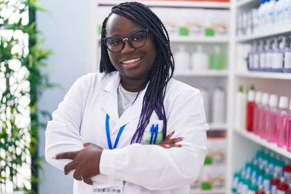 アフリカ系アメリカ人女性薬剤師笑顔自信を持って立ってとともに腕交差ジェスチャーで薬局 — ストック写真