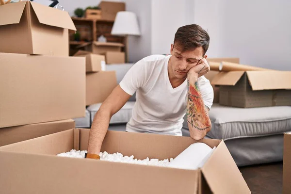 Young Man Unpacking Cardboard Box Unhappy Expression New Home — Stockfoto