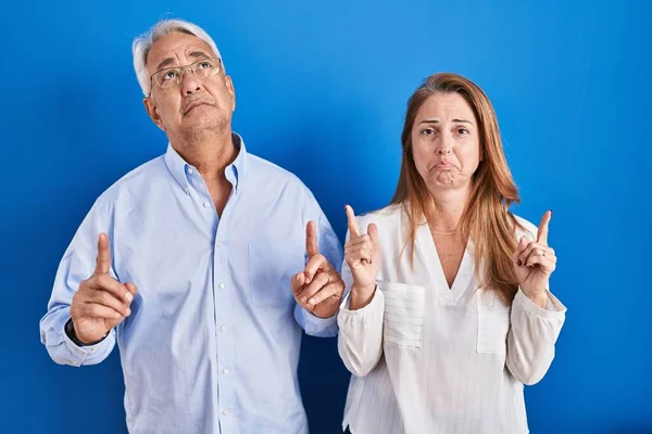 中年时 他的一对惊慌失措的夫妇站在蓝色的背景上 带着忧郁和不安的样子 用手指指示方向 不快乐和沮丧 — 图库照片