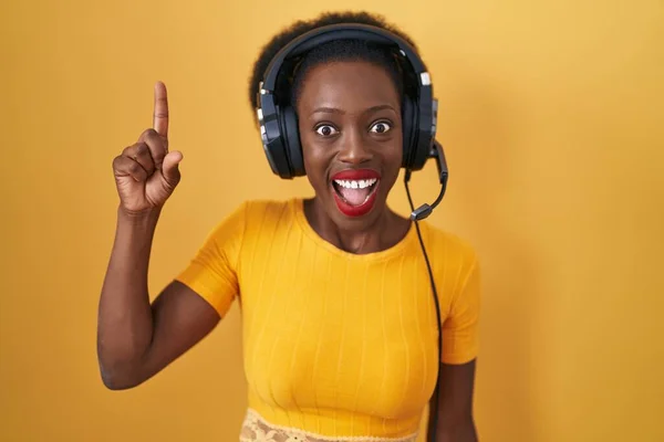 Afrikai Göndör Hajjal Áll Sárga Háttér Felett Fülhallgatóval Mutogatva Sikeres — Stock Fotó