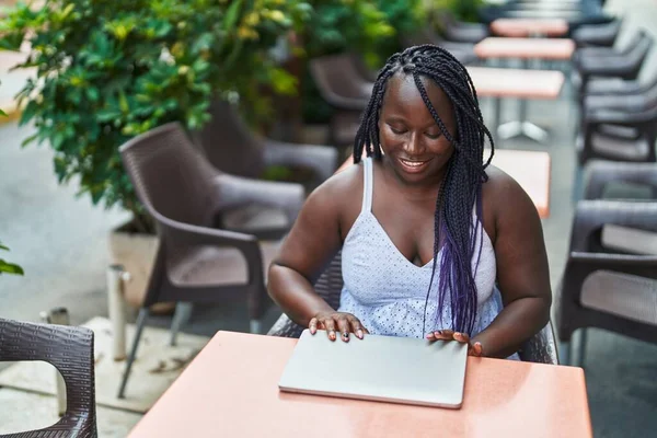 アフリカ系アメリカ人女性がコーヒーショップのテラスでテーブルの上に座ってノートパソコンを閉じる — ストック写真