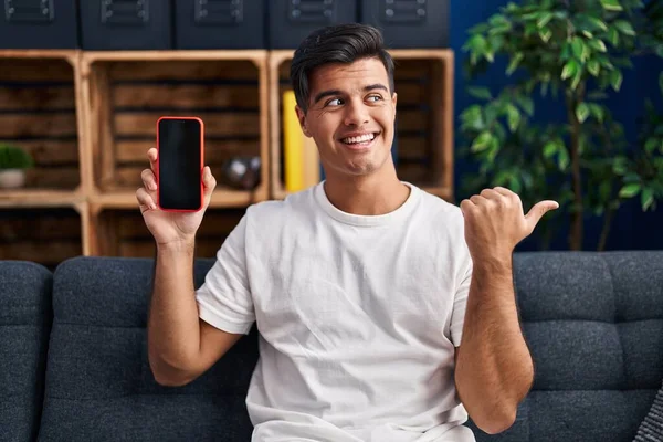 Hispanic Man Holding Smartphone Showing Blank Screen Pointing Thumb Side — Stock Photo, Image