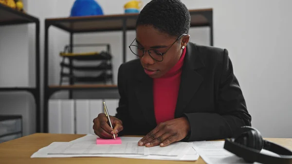 アフリカ系アメリカ人女性ビジネスワーカーが事務所で書類を書く — ストック写真