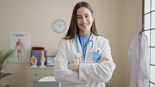 Genç Beyaz Kadın Doktor Gülümsüyor Klinikte Kollarını Kavuşturup Duruyor — Stok fotoğraf
