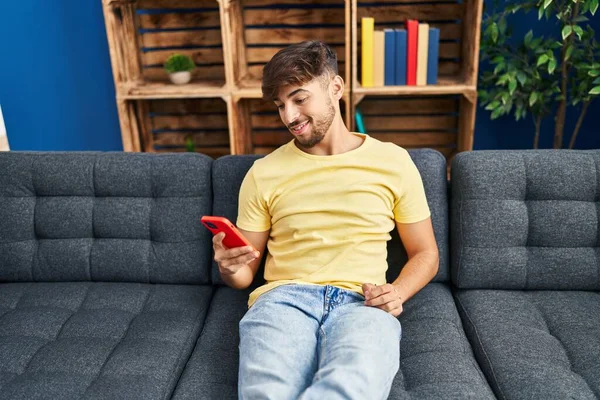 Jonge Arabier Man Met Smartphone Zittend Bank Thuis — Stockfoto