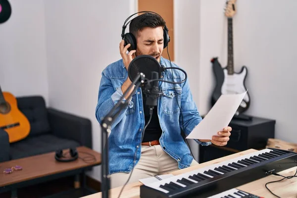 Young hispanic man singing song at music studio