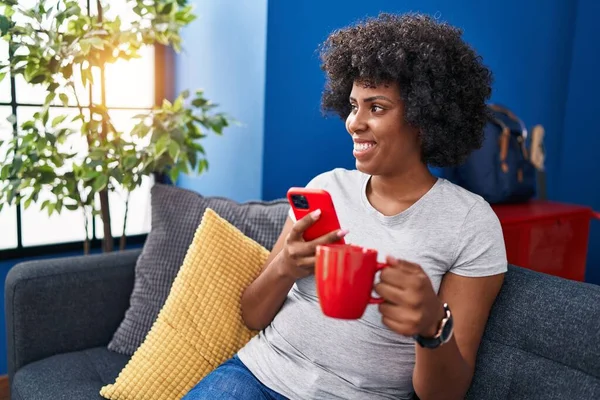 Afro Amerikalı Kadın Akıllı Telefon Kullanıyor Evde Kahve Içiyor — Stok fotoğraf