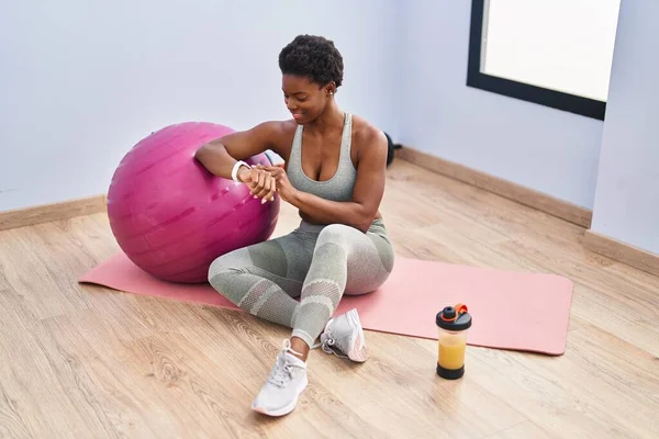 Afroamerikanerin Sitzt Mit Stoppuhr Auf Yogamatte Sportzentrum — Stockfoto