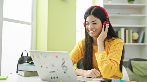図書館大学でヘッドフォンを身に着けているコンピュータを使用して若い美しいヒスパニック女性学生 — ストック写真