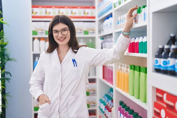 年轻的高加索女药剂师微笑着 自信地将药品放在药库中 — 图库照片