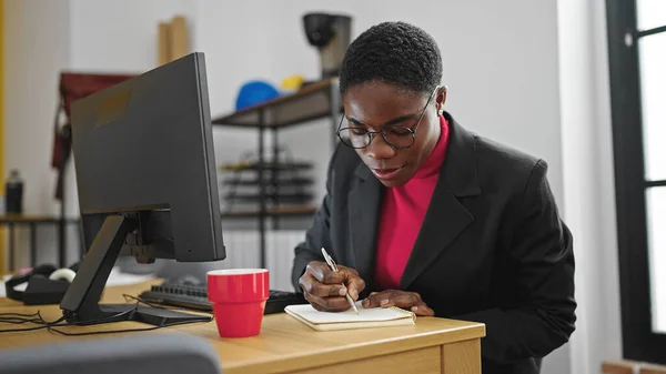 アフリカ系アメリカ人の女性ビジネスワーカーがオフィスでノートを書く — ストック写真