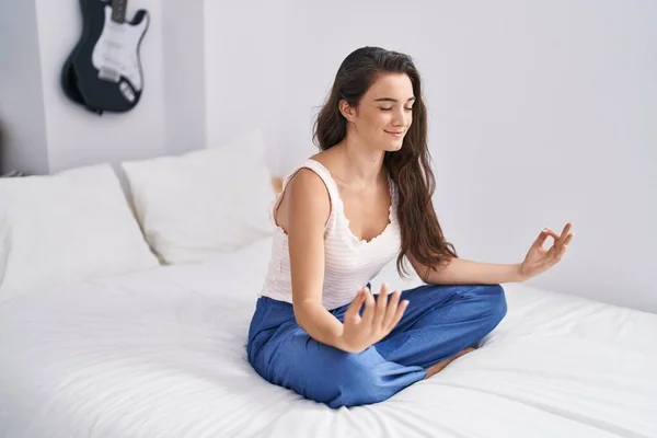 年轻的惊慌失措的女人坐在床上做瑜伽练习 — 图库照片