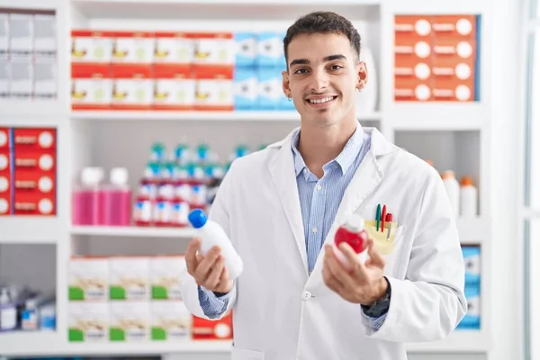 Jovem Homem Hispânico Farmacêutico Sorrindo Confiante Segurando Garrafas Medicação Farmácia — Fotografia de Stock