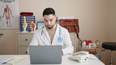 Genç Arap doktor klinikte çalışırken dizüstü bilgisayar kullanıyor.