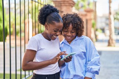 African american women mother and daughter using smartphone at street