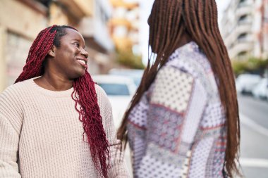 African american women friends standing together speaking at street