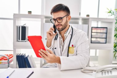 Genç İspanyol doktor dokunmatik ped kullanıyor. Klinikte Samrtphone ile konuşuyor.