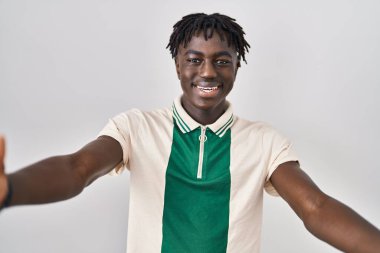 Afrikalı bir adam, izole edilmiş arka planda durup kameraya bakarak sarılmak için kollarını açmış gülümsüyor. Mutluluğu kucaklayan neşeli bir ifade.. 