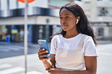 Young african american woman listening to music at street