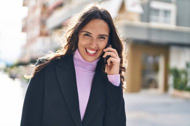 Genç İspanyol kadın gülümsüyor. Kendine güveniyor. Akıllı telefondan konuşuyor.