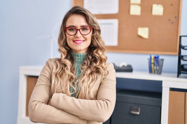 Young woman business worker standing with arms crossed gesture at office