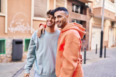 İki erkek caddede birbirlerine sarılıyorlar.