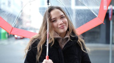 Young beautiful hispanic woman smiling confident holding umbrella at street