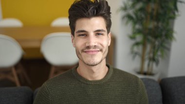 Evdeki kanepede kendinden emin gülümseyen İspanyol genç adam.