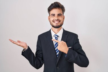 İş elbisesi giyen ve kravat takan İspanyol asıllı genç adam kameraya hayret ediyor ve gülümsüyor.. 