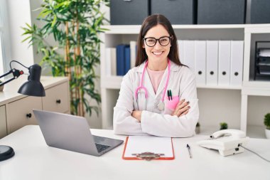 Klinikte çalışan doktor üniforması giyen genç bir kadın.