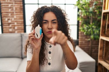 Glikoz ölçer kullanan genç bir İspanyol kadın kamerayı işaret ediyor ve sen kendine güvenen ciddi bir hareket yapıyorsun. 