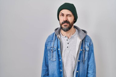 Dövmeli, yün şapkalı genç İspanyol adam kameraya seksi bir ifadeyle bakıyor, neşeli ve mutlu bir yüz.. 