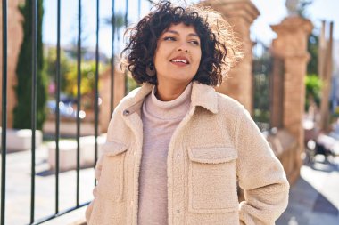 Young beautiful hispanic woman smiling confident looking to the side at street