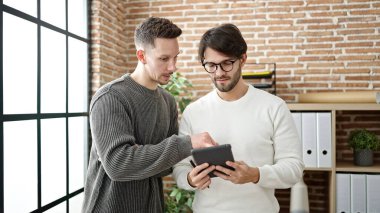 Ofiste çalışan iki erkek iş ortağı touchpad kullanıyor.