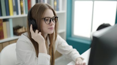 Young blonde woman student using computer studying at university classroom