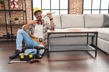 Sakallı genç İspanyol adam, hareket servisi üzerinde çalışıyor. Gülümsüyor, mutlu bir şekilde eli ve parmağı işaret ediyor. 