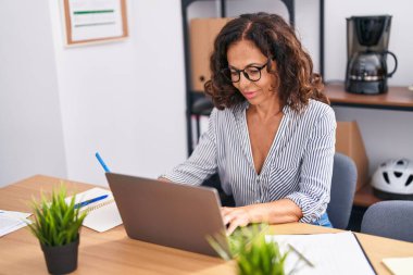 Middle age woman business worker using laptop and touchpad at office