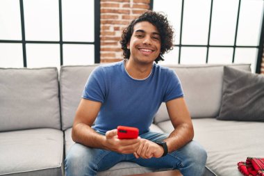 Genç İspanyol adam akıllı telefon ve akıllı telefon kullanıyor.