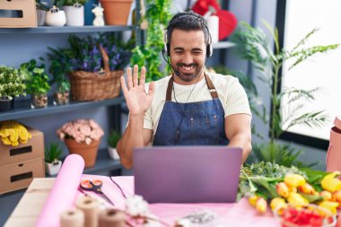 Çiçekçide sakallı İspanyol bir adam çalışıyor. Laptop kullanıyor. Pozitif ve mutlu görünüyor. 